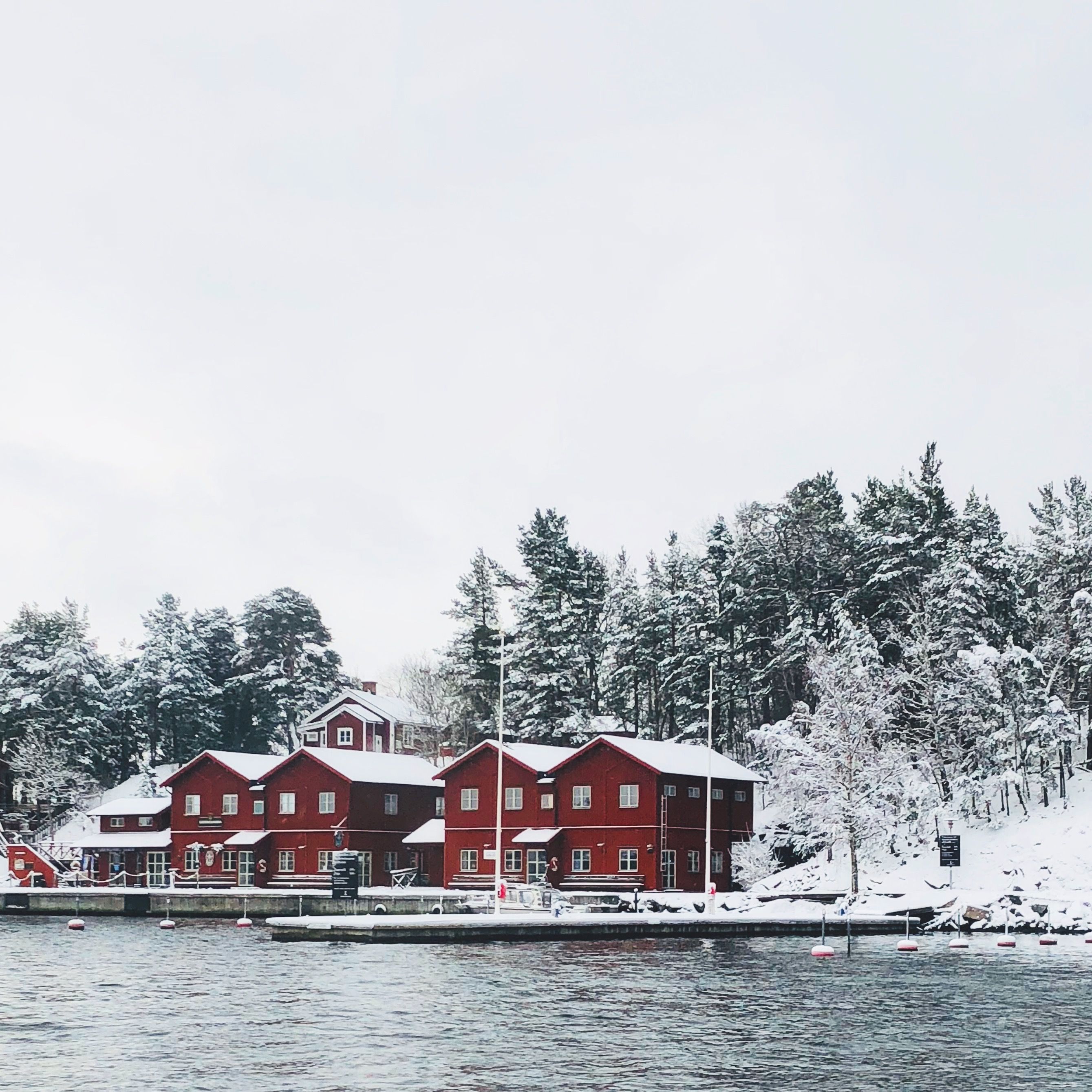 Röda trähus vid vattnet en snöig vinterdag